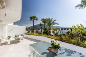 patio ze stołem, krzesłami i palmami w obiekcie Bella Vista Puerto Banus apartment with sea views w Marbelli