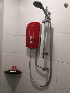a shower with a red dispenser on a wall at W Hotel Cemerlang in Kota Bharu