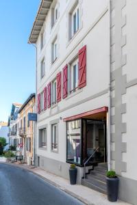 a white building with red windows on a street at Hotel Villa Koegui Biarritz in Biarritz