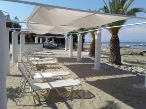 a row of white chairs under a canopy on the beach at UMBRELLA BEACH APARTMENTs in Kavos
