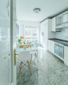 a white kitchen with a white table and chairs at HyP - LA CASA DE LAS HORTENSIAS in Pontevedra