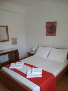 a bedroom with a large bed with a red blanket at ziogas apartments in Plataria