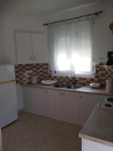 a kitchen with white cabinets and a sink and a window at ziogas apartments in Plataria