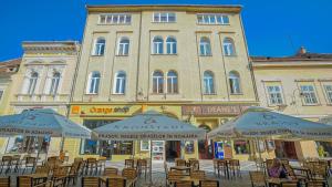 un edificio con mesas y sombrillas delante en Zoom Rooms en Brasov