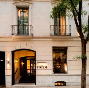 una tienda frente a un edificio con un árbol en TÓTEM Madrid, a Small Luxury Hotel of the World, en Madrid