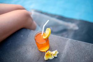 a drink with a slice of orange and flowers on a table at Tom's Inn Pecatu in Uluwatu