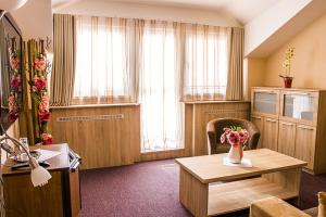 una sala de estar con una mesa con un jarrón de flores en Hotel Kamei, en Snina