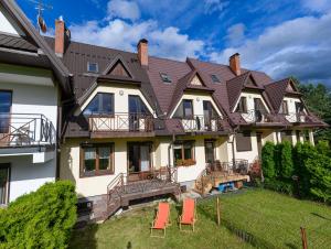 an exterior view of a large house with red chairs at VisitZakopane - Mountain Home Apartment in Zakopane