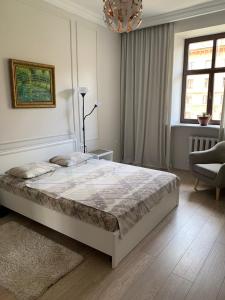 a white bedroom with a bed and a chair at KAZA APART in Minsk