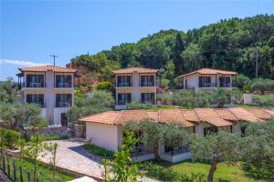 a row of houses on a hill with trees at MEGA AMMOS HOTEL in Sivota