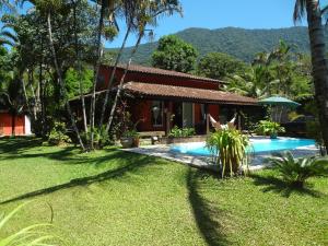 a house with a swimming pool in front of a yard at Cantinho da Tia Helo in Maresias
