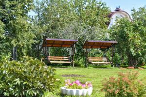 ベロクリハにあるОтель "Белокуриха"の木々と花の庭のベンチ2つ