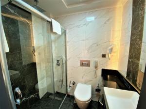 a bathroom with a shower and a toilet and a sink at MİYAS LUXURY HOTEL in Kemer