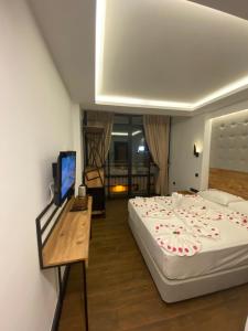 a bedroom with a bed and a desk with a television at MİYAS LUXURY HOTEL in Kemer