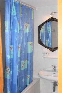 a bathroom with a shower curtain with a sink and a mirror at Hotel zur Post Schwanheim in Frankfurt