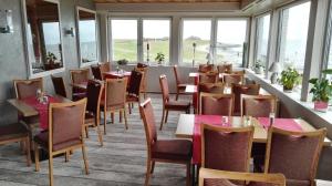 um restaurante com mesas, cadeiras e janelas em Strandhotel Dagebüll direkt an der Nordsee em Dagebüll