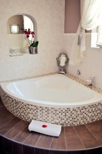 y baño con bañera grande y espejo. en Bokmakierie Gastehuis Emalahleni Pty Ltd en Witbank