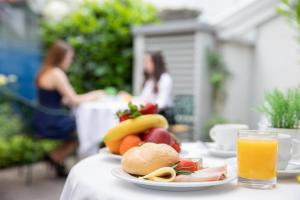 un piatto di frutta su un tavolo con un bicchiere di succo d'arancia di Hotel Gollner a Graz Altre 37 foto