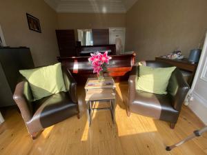 uma sala de estar com duas cadeiras e uma mesa com flores em Ardmhor Guest House em Oban