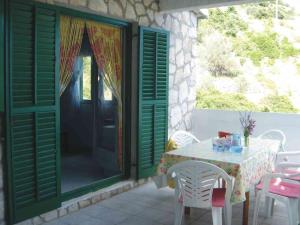 een tafel en stoelen op een patio met groene deuren bij Apartment Vjeka in Vela Luka