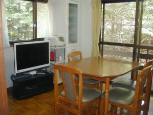 una sala da pranzo con tavolo e TV di Cottage Karuizawa a Karuizawa