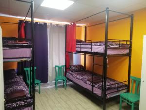 a room with three bunk beds and two chairs at Hostel Meridian in Kyiv