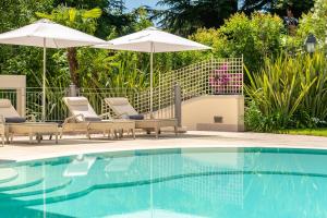 a patio area with a pool, chairs, and an umbrella at Villa Rosa Hotel Desenzano in Desenzano del Garda