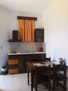 eine Küche mit einem Tisch und einem Waschbecken sowie einem Tisch und Stühlen in der Unterkunft Armonia by Grispos Villas in Schinoussa