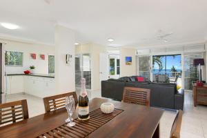 a living room with a table with a bottle of wine at The Beach House 3BR Waterfront Apartment, Own WIFI in Trinity Beach