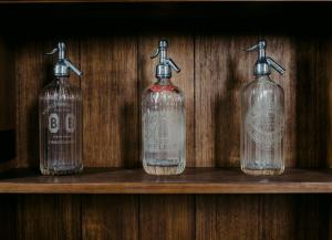 four empty bottles sitting on a wooden shelf at The Old Confectionery in Oamaru