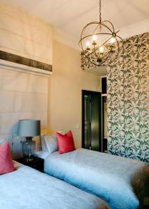 a bedroom with two beds and a chandelier at The Old Confectionery in Oamaru