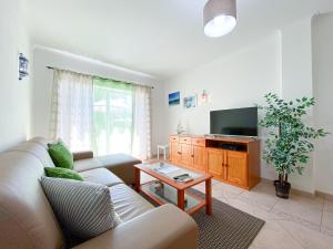 a living room with a couch and a tv at Casa do Farol - Apartamento com piscina junto à Praia do Camilo in Lagos