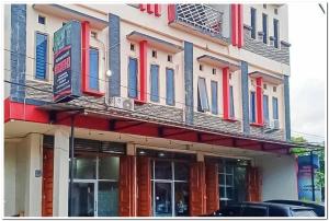 um edifício com portas e janelas vermelhas e azuis em Hotel Dheadita Syariah Sungai Penuh Mitra RedDoorz em Sungaipenuh