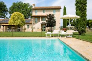 einen Pool vor einem Haus mit Stühlen und einem Sonnenschirm in der Unterkunft Demetra in Papiano