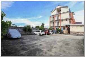 a parking lot with cars parked in front of a building at The Nancy's Homestay Pekanbaru Mitra RedDoorz in Pekanbaru