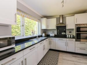 a kitchen with white cabinets and a large window at Trevore Farmhouse in Truro