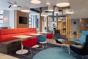 Un vestíbulo con un sofá rojo, mesas y sillas. en Holiday Inn Express Belfast City by IHG, en Belfast