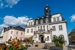 ein großes weißes Gebäude mit einem Uhrturm in der Unterkunft Hotel Ratskeller Schwarzenberg in Schwarzenberg