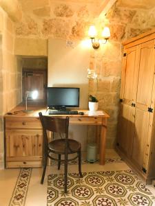 uma secretária com um computador e uma cadeira num quarto em L'Gharix Temple Retreat em Xaghra