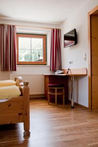 a bedroom with a bed and a desk and a window at Hotel & Suites Glück Auf in Mayrhofen