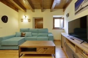a living room with a blue couch and a tv at Aizkolarienea in Ochagavía