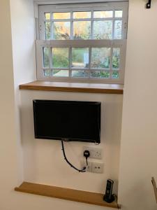 TV de pantalla plana en una pared bajo una ventana en The Studio @ The Old Vicarage en Pendeen