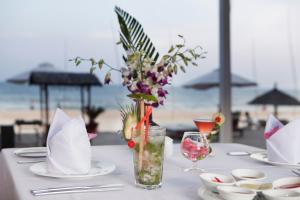 a table with white plates and a vase with flowers at Blue Ocean Resort in Mui Ne