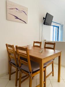 a dining room table with four chairs and a tv at Spanos Apartments in Agios Petros