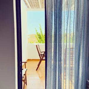 a room with a balcony with a chair and a window at Spanos Apartments in Agios Petros