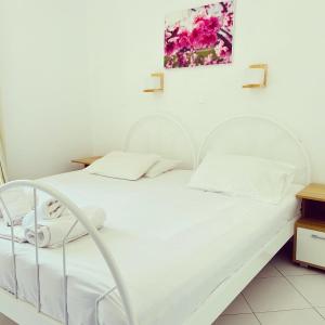 a bedroom with a white bed and a painting on the wall at Spanos Apartments in Agios Petros