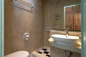 a bathroom with a white sink and a toilet at Kalamitsi Hotel in Kardamyli