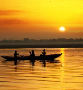 een groep mensen in een boot op het water bij zonsondergang bij Amritara Suryauday Haveli in Varanasi