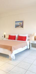 a white bedroom with a large bed with red pillows at The White Apartment in Ohrid