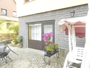 patio z czarnymi drzwiami oraz krzesłami i kwiatami w obiekcie Ferienwohnungen Langer w mieście Altenberg